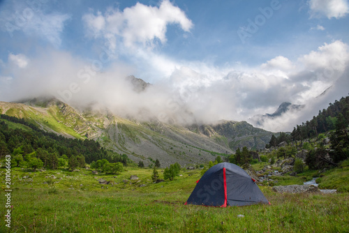 Tourist tent stands on a green meadow against the backdrop of mountains in the valley of Goralykol, Teberda, Karachay-Cherkessia, Russia