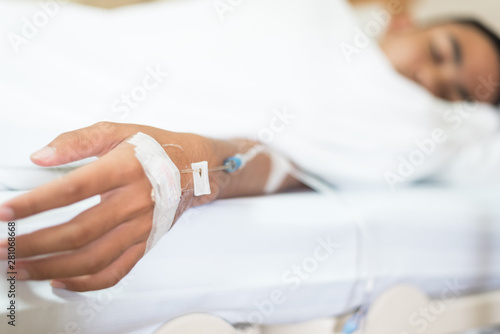 Selective focus young boy hand and set iv fluid intravenous drop saline drip on hospital bed.Medical treatment concept.