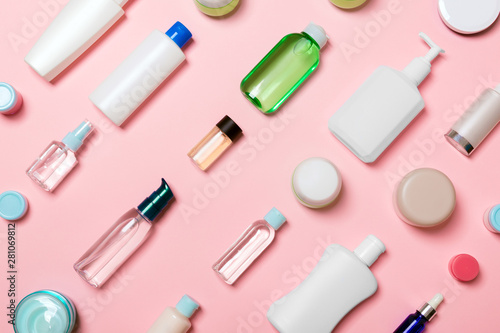 Top view of different cosmetic bottles and container for cosmetics on pink background. Flat lay composition with copy space