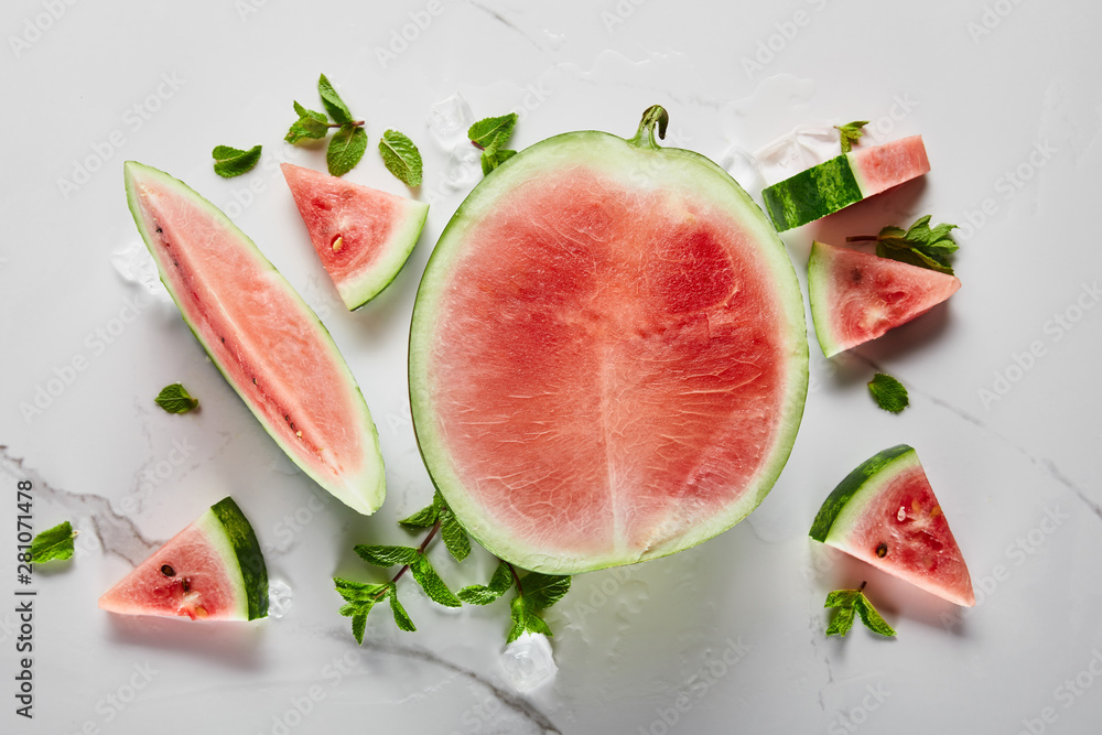 top view of cut delicious exotic red watermelon with seeds on marble surface with ice and mint top view of cut delicious exotic red watermelon with seeds on marble surface with ice and mint
