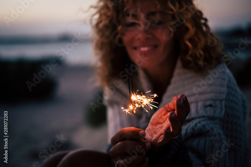 New year eve or celebration time for cheerful lady in the evenign night with fire sparklers - focus on fire and defocused portrait in backgrouind - concept of celebration and romance