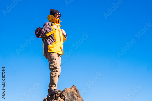 Standing happy man with backpack and hiking equipment on the top of the mountain - concept of hike and travel for people enjoy the outdoor leisure activity in sport adventure alternative lifestyle