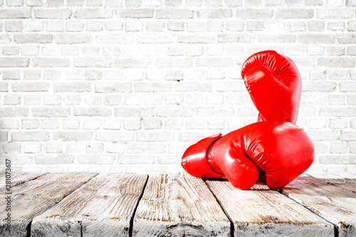 Red boxing gloves on wooden top background. © magdal3na