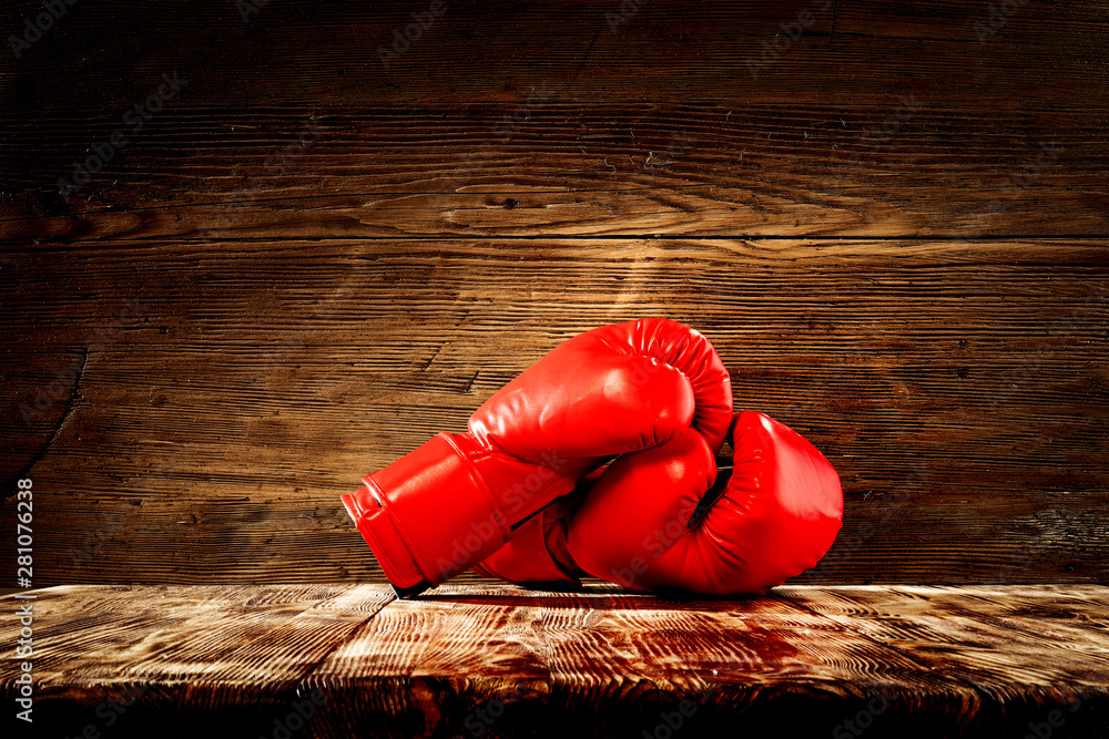 Red boxing gloves on wooden top background.