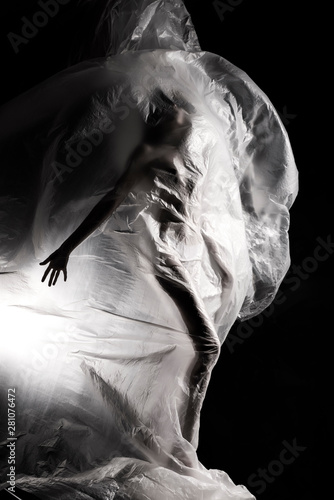 Billede på lærred Slim girl dressed only in underwear emotionally posing, wrapped in fluttering in the wind and fitting her graceful young body cellophane film