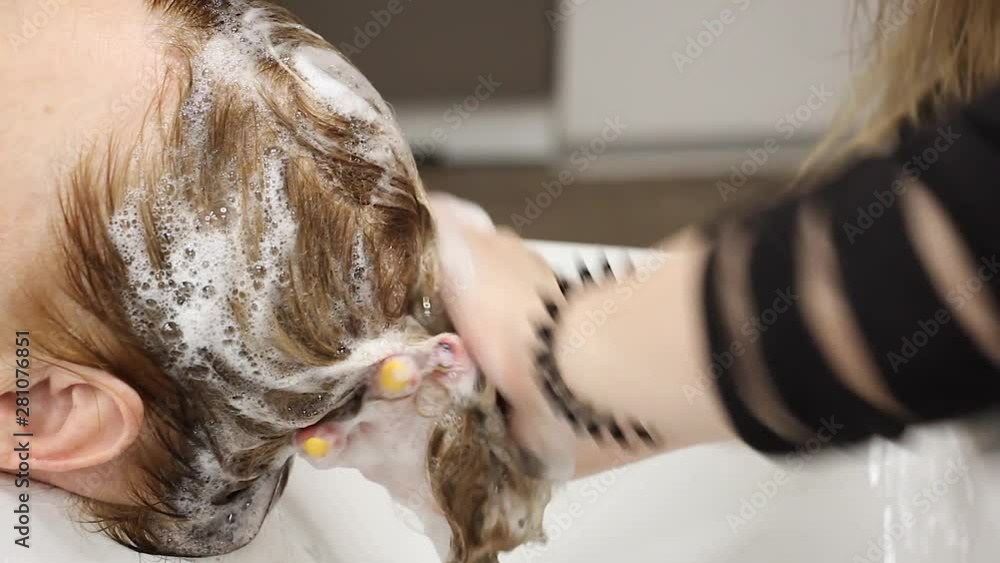 stylist hands washes hair for client with shampoo foam and massages head, training at hairdresser workshop, close-up stylist hands washes hair for client with shampoo foam and massages head, training at hairdresser workshop, close-up