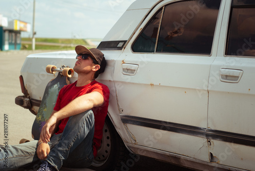 Young skater in the red shirt resting at the old cars, the journey to longbone, photo