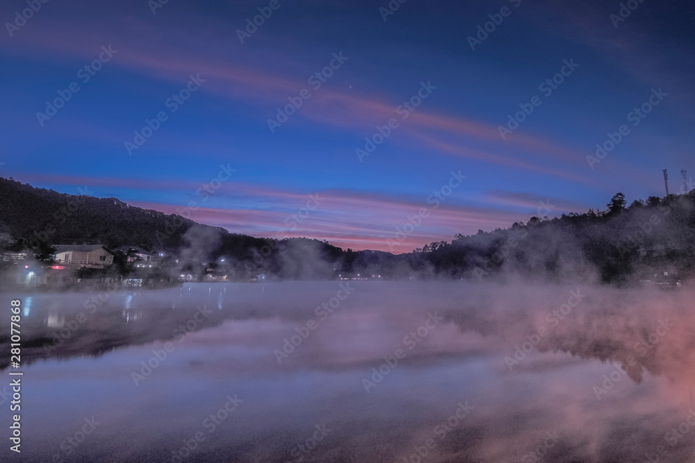 Lake view morning of the mist rising up from the water around with the hill, mountain and blue sky background, sunrise at Ban Rak Thai, Mae Hong Son, northern of Thailand. Lake view morning of the mist rising up from the water around with the hill, mountain and blue sky background, sunrise at Ban Rak Thai, Mae Hong Son, northern of Thailand.