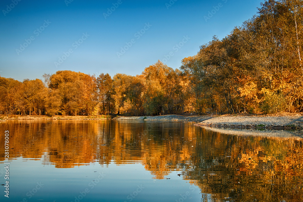 Beautiful autumn landscape. Golden forest and lake in sunny weather