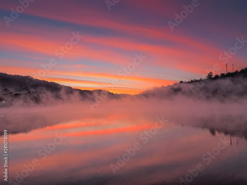 Lake view morning of the mist rising up from the water around with the hill, mountain and red sky background, sunrise at Ban Rak Thai, Mae Hong Son, northern of Thailand.