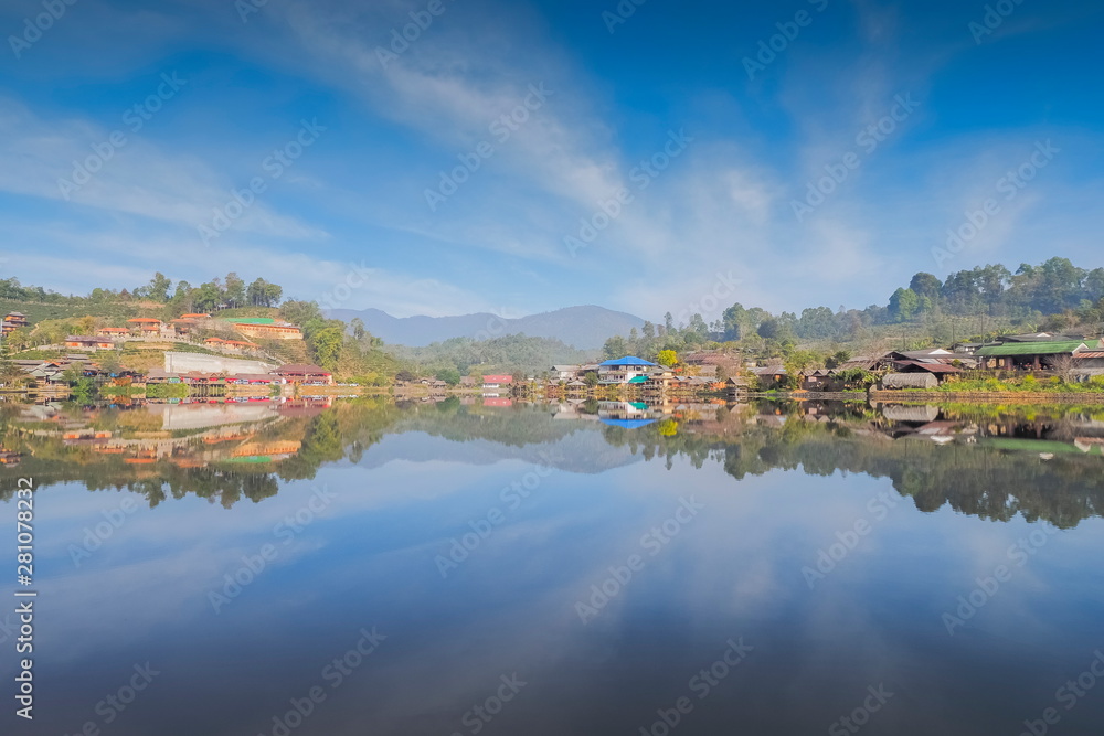 view morning of Ban Rak Thai Village on the bank of reservoir with green hill and cloudy sky background, Ban Rak Thai Reservoir, Mae Hong Son, northern of Thailand.