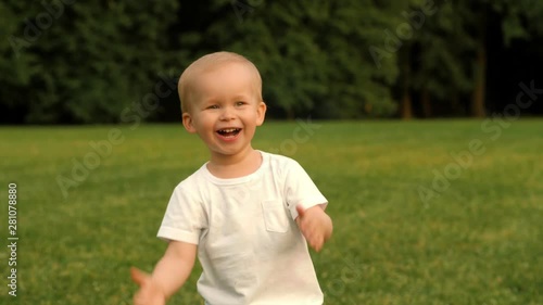 Portrait of smiling baby boy clapping hands surrounded by summer forest park