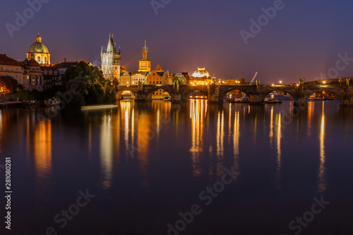 Charles Bridge between districts Old Town and Lesser Town at night in Prague. Old Town tower and historic stone bridge over the Vltava with illumination. Reflection of the colorful lights on the water © Marco
