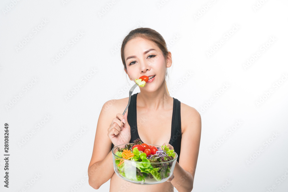 Asian young woman with healthy food in fitness suit holding her fried salad bowl isolated on a white background. Asian young woman with healthy food in fitness suit holding her fried salad bowl isolated on a white background.