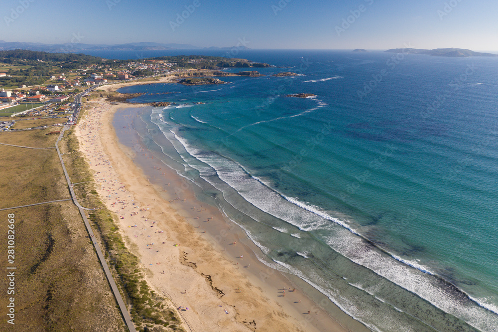 ocean waves, sandy beach with people bathing in the water, view from drone, Lanzada beach, Galicia, Spain