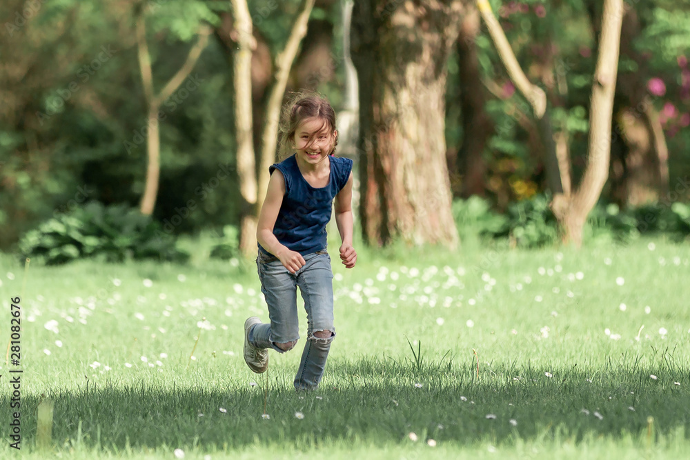 happy little girl running across the meadow on a summer day.