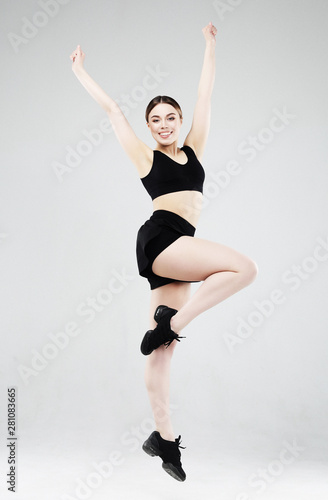 Sport, fitness and people concept: Beautiful young woman dressed in sportswear jumping up over grey background