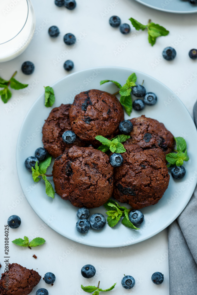 Chocolate cookies with chocolate chips and blueberry on gray wooden background. Summer food. Soft focus. Top view. Chocolate cookies with chocolate chips and blueberry on gray wooden background. Summer food. Soft focus. Top view.