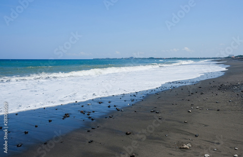 Ocean coast with black volcanic sand on the island of Bali  Indonesia.