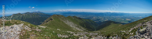 wide panoramic view with top of Baranec peak on Western Tatra mountains or Rohace panorama. Sharp green mountains with hiking trail on ridge. and Liptov valley. Summer blue sky background