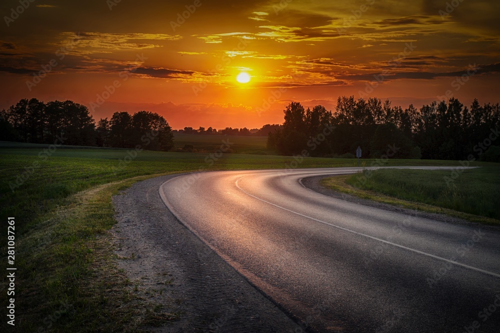 Vivid orange tropical sunset with curving road