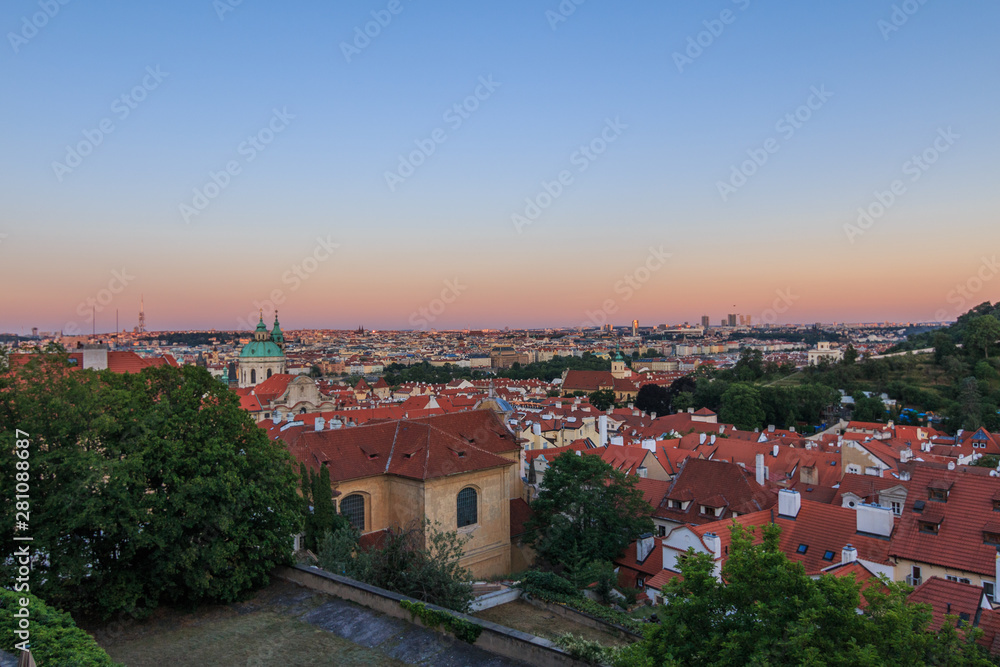 View over Prague in the evening. Red evening sun colors the horizon. Cityscape of Prague Castle above the roofs of the Lesser Town and Old Town districts