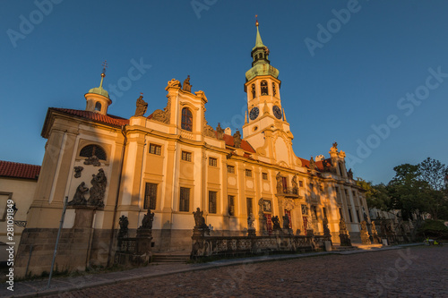 Capuchin Church Loreta from Hradcany Square near the Prague Castle. View of the historic Baroque building complex in the Czech capital from the left in the evening sun with blue sky