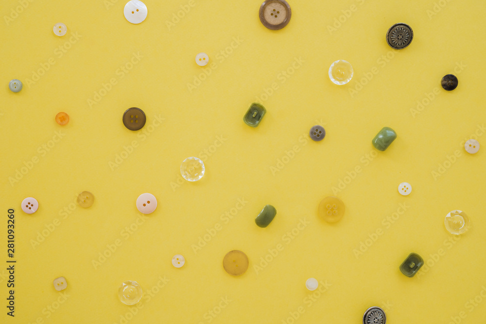 An overhead view of buttons on yellow backdrop An overhead view of buttons on yellow backdrop