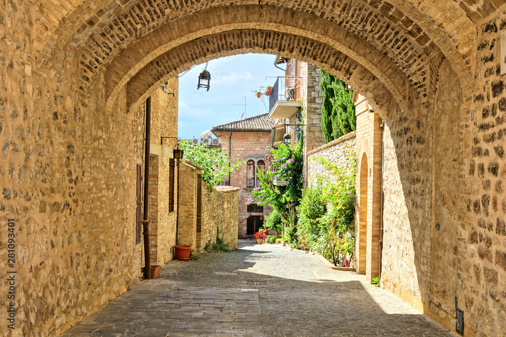 Naklejka Średniowieczne budynki starego miasta w Asyżu poprzez malowniczy kamienny łuk, Włochy