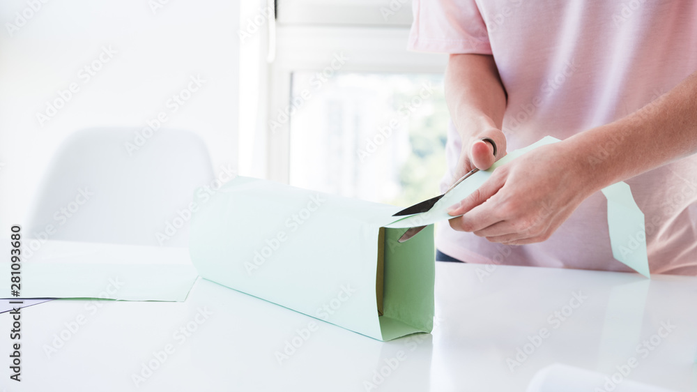 Woman's hand cutting the paper wrapped on box with scissor