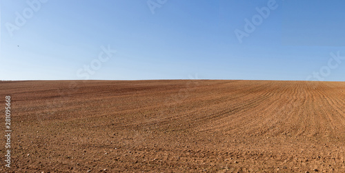 Vista panorámica de loma de  terreno agricola  arado recientemente y preparados para el cultivo y cielo azul