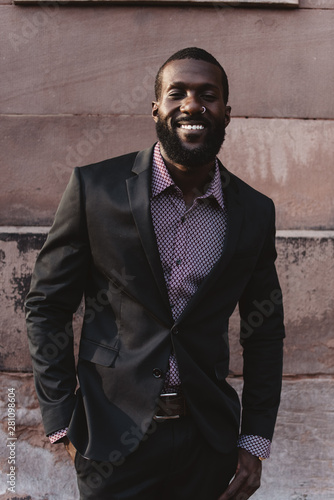 A young black man in his twenties wearing a suit in the city