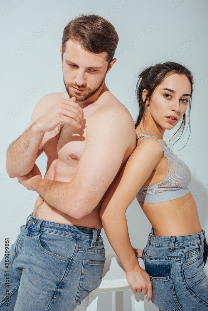 handsome muscular guy looking away while girl standing near man and looking at camera handsome muscular guy looking away while girl standing near man and looking at camera