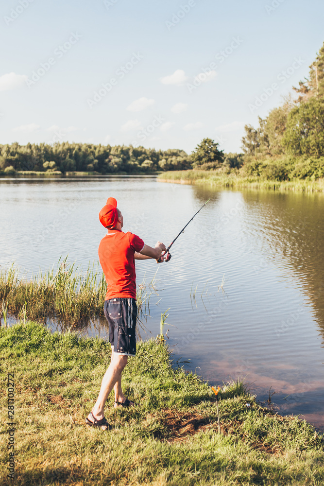 Fisherman on the bank throws a fishing rod into the river - amateur fishing in fresh water Fisherman on the bank throws a fishing rod into the river - amateur fishing in fresh water