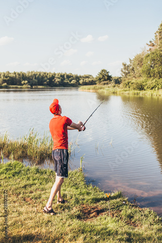Fisherman on the bank throws a fishing rod into the river - amateur fishing in fresh water