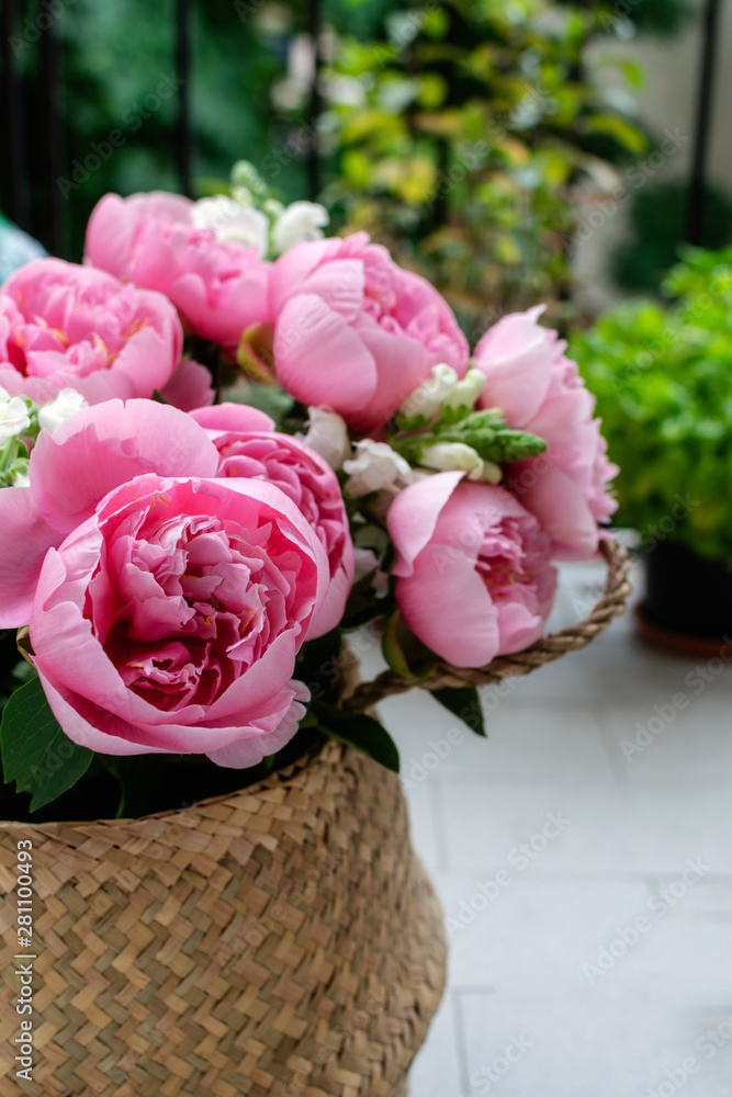 Bouquet of beautiful pink peonies in straw basket Bouquet of beautiful pink peonies in straw basket