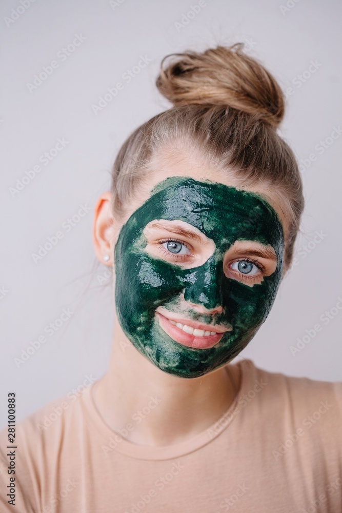 Lovely blond female with green skincare mask on her face Lovely blond female with green skincare mask on her face