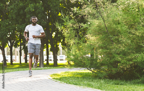 Konstfotografi Sporty afro guy with headset is running in the park