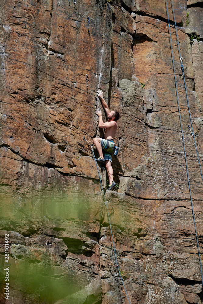 Side view of shirtless man rock climbing on mountain Side view of shirtless man rock climbing on mountain