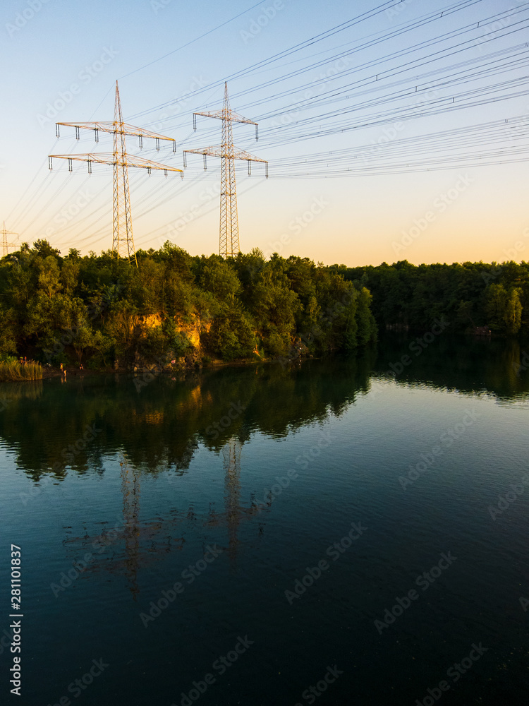 Two electricity pylons surrounded by trees in autumn on a lake