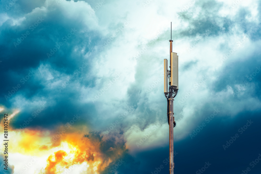 A column with transmitters and mobile telephony antennas against the sky with clouds at sunrise