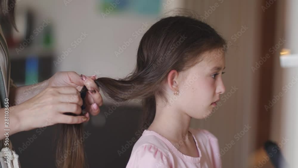 Mom braids and comb a little upset daughter. Mom braids and comb a little upset daughter.