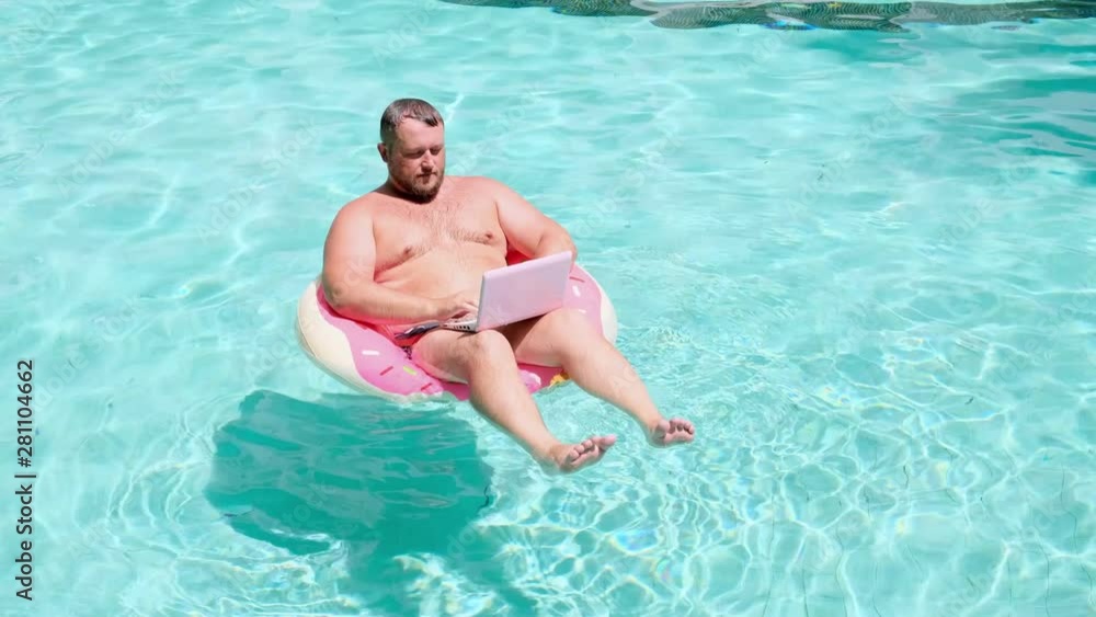 Male businessman with a laptop on rubber ring in the water Male businessman with a laptop on rubber ring in the water