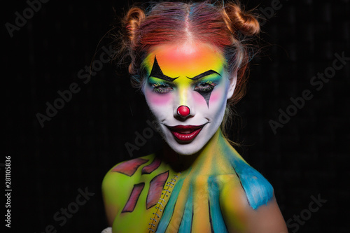Foto Lovely young woman with a face painting clown.