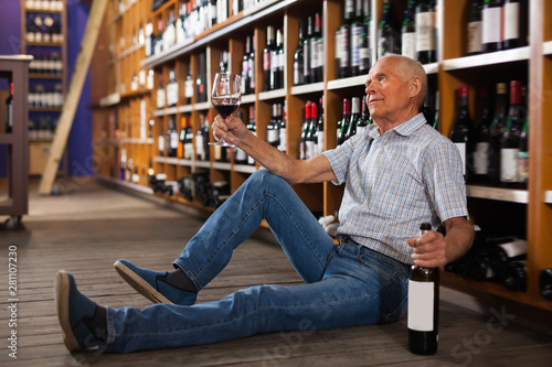 Adult man tasting red wine sitting on floor