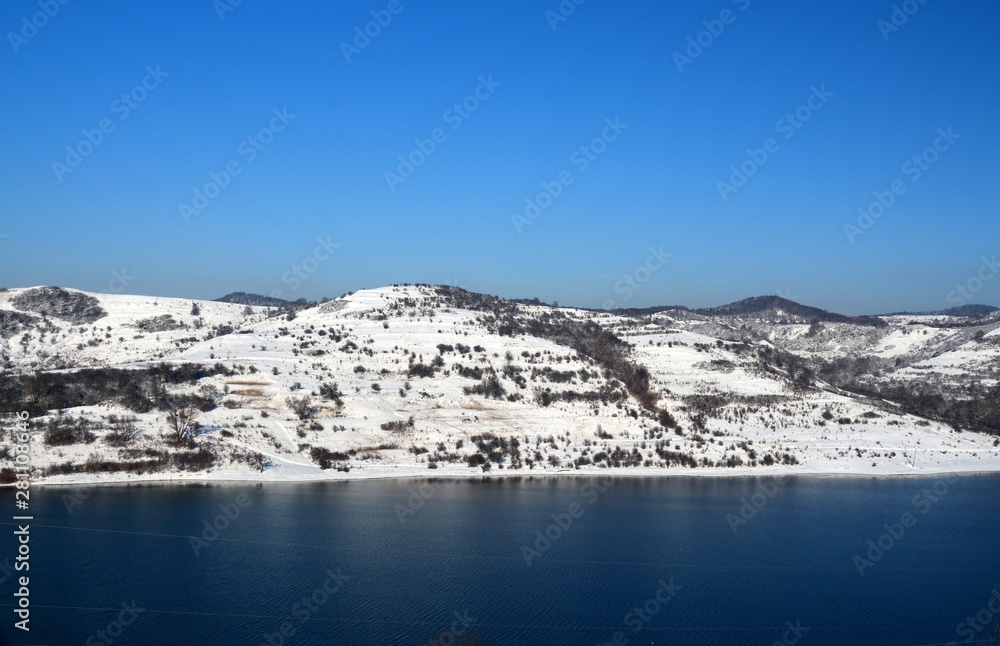 A lake near a hill covered with snow