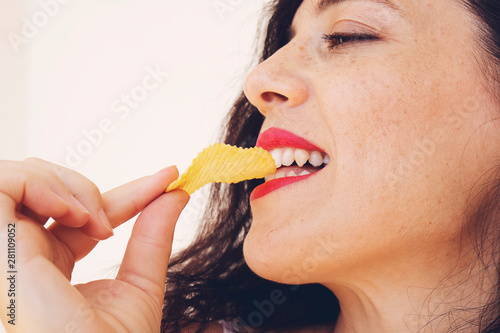 blond girl eating potato chips on white background © batuhan toker