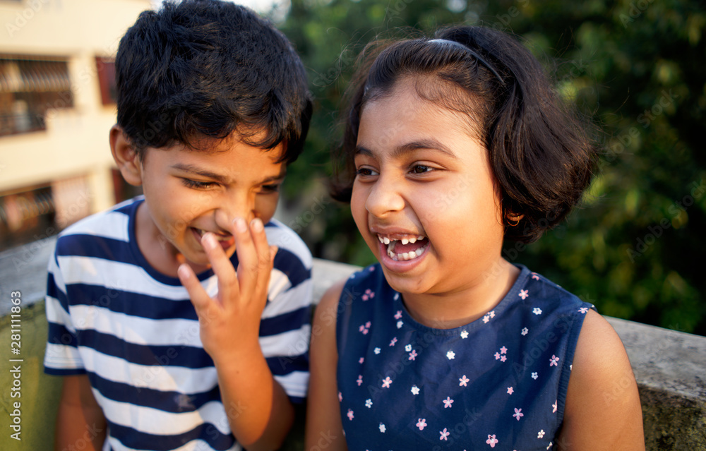 Young boy sharing a secret with his younger sister,having fun Stock