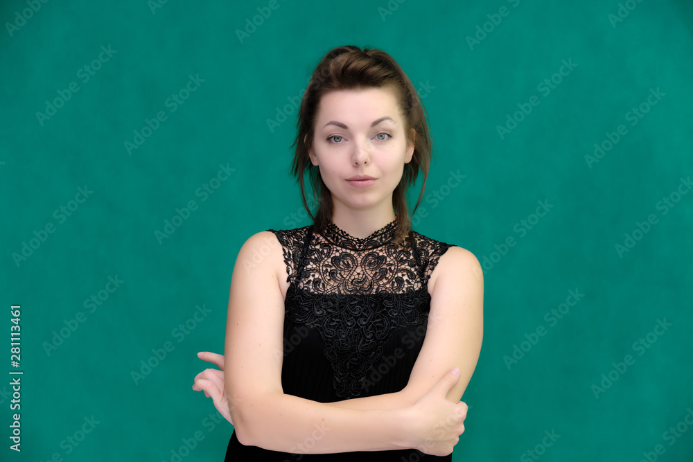 Portrait of a pretty beautiful fashionable adult brunette girl in a black dress on a green background. Standing right in front of the camera, showing different poses and emotions. Portrait of a pretty beautiful fashionable adult brunette girl in a black dress on a green background. Standing right in front of the camera, showing different poses and emotions.
