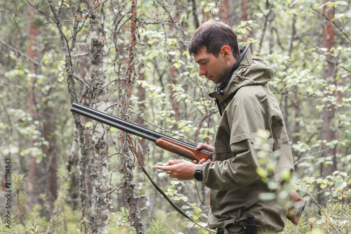 Hunter in the forest in hunting season. Leisure on hunting. Young forester hold rifle.